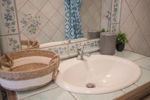 a bathroom with a sink and a basket and a mirror at Gites au Cœur de la Nature, Piscine et Vue sur le Lac du Salagou in Le Puech