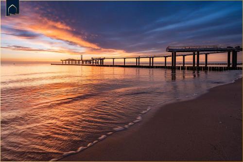 a pier on the beach with the ocean at Hart Backbord in Loddin