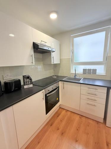 a kitchen with white cabinets and a sink and a window at Deluxe Studio in Heart of town in Gibraltar