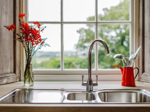 a kitchen sink with a vase of flowers and a window at 4 Bed in Padstow PENDA in Egloshayle