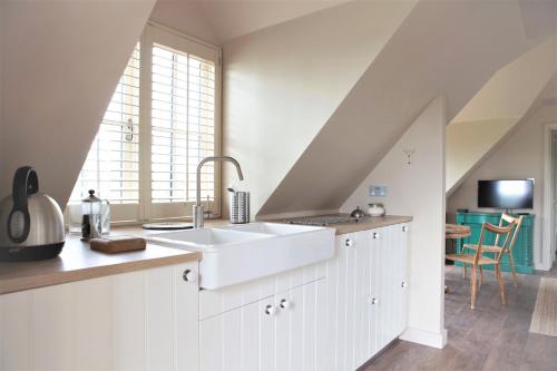 a white kitchen with a sink and a window at The Lakehouse Apartment by inspirestays-com in Rudgwick