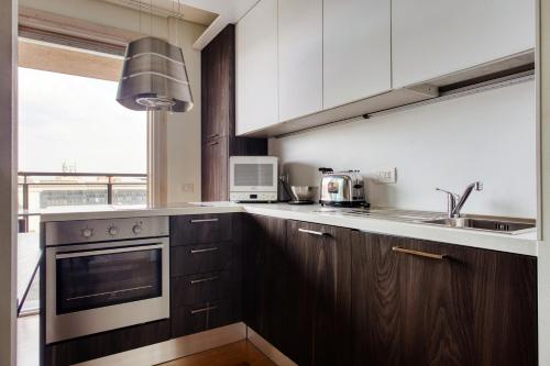 a kitchen with wooden cabinets and a sink and a microwave at GiaxTower Gym Spa & Pool Bright Space 6' piano in Milan