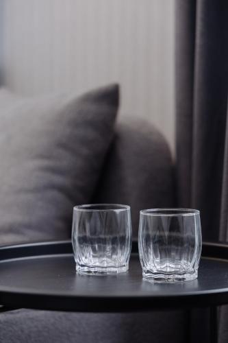 two empty glasses sitting on a table next to a couch at TÖR by Uly Dala Hotels in Kostanay