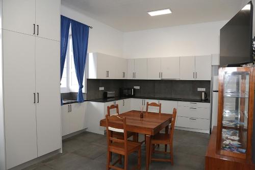 a kitchen with white cabinets and a wooden table and chairs at Casa Senhor da Pedra in Vila Franca do Campo