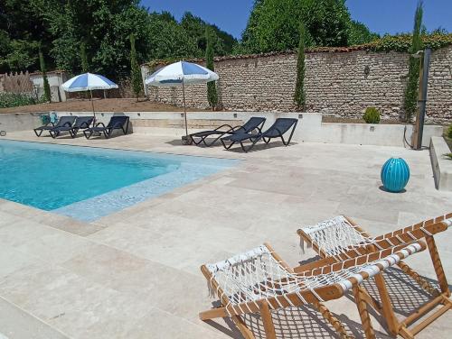 a swimming pool with chairs and umbrellas next to a swimming pool at Gîte de charme dans ancienne seigneurie in Le Pin-Saint-Denis