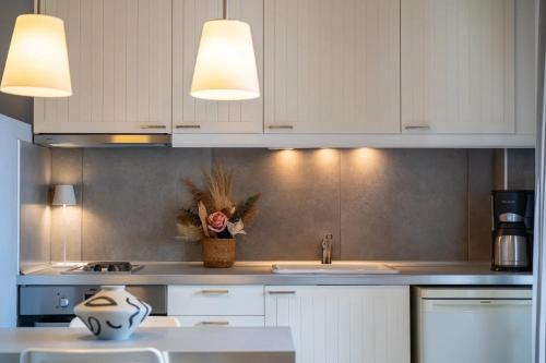 a kitchen with white cabinets and a vase of flowers at Filina House in Neos Marmaras