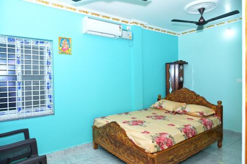 a blue bedroom with a bed and a ceiling fan at SRIVALLI Lodge in Avanigadda