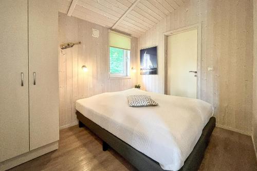 a bedroom with a large white bed with a window at Pulverhorn - Dorf 4 Ferienhaus 3 in Priwall