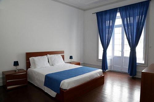a bedroom with a large bed with blue curtains at Casa Senhor da Pedra in Vila Franca do Campo