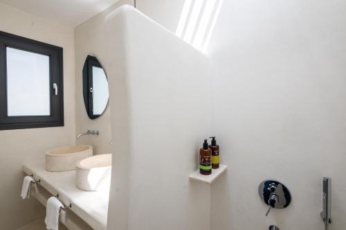 a white bathroom with a sink and a mirror at Myconian Theros Luxury Suites in Ano Mera