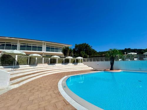 a swimming pool in front of a building at Camping Le Parc des Chênes in La Croix-Valmer