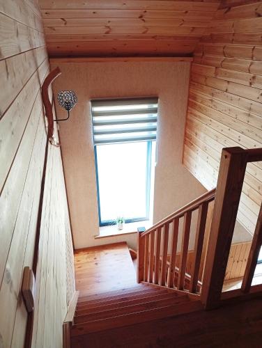 a staircase in a wooden cabin with a window at Wooden House Close to the Beach in Pērkone