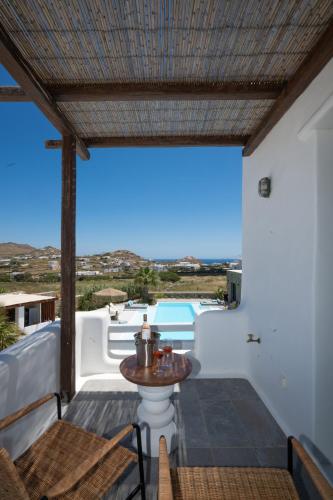 a patio with a table and a view of a pool at Myconian Theros Luxury Suites in Ano Mera