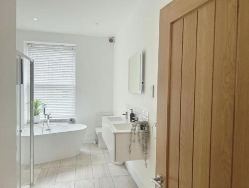 a white bathroom with a tub and a sink at Barbican Boutique Luxury Apartments & Rooms, Plymouth in Plymouth