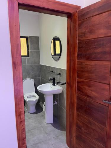 a bathroom with a toilet and a sink and a door at The Max Guest House in Teiman