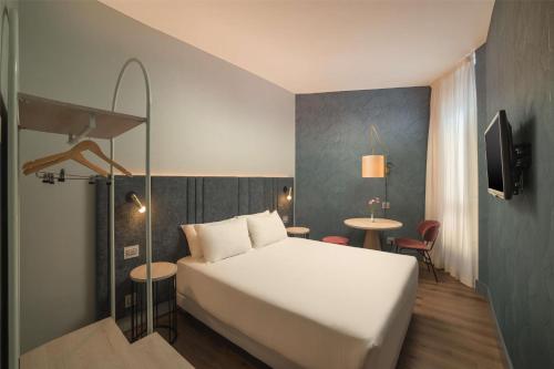 a bedroom with a white bed and a table at NH La Spezia in La Spezia