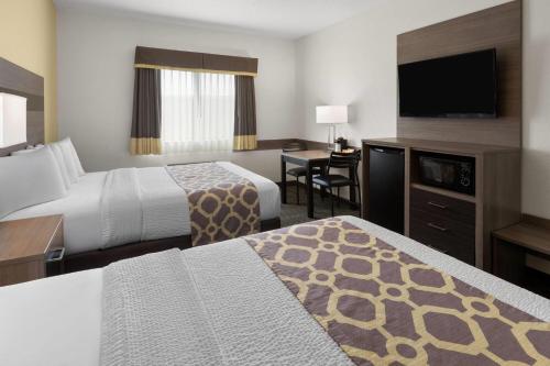 a hotel room with two beds and a flat screen tv at Baymont by Wyndham Paw Paw in Paw Paw