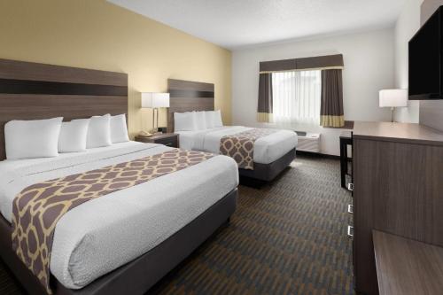 a hotel room with two beds and a television at Baymont by Wyndham Paw Paw in Paw Paw
