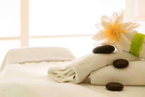 a pile of towels on a bed with a flower on top at Dolce by Wyndham Bad Nauheim in Bad Nauheim
