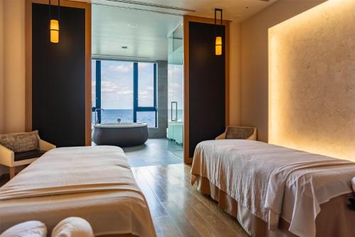 two beds in a room with a bath tub at Hyatt Regency Seragaki Island Okinawa in Onna