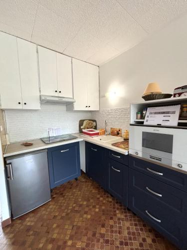 - une cuisine avec des placards bleus et blancs et un four micro-ondes dans l'établissement La belle onde, à Mimizan-Plage