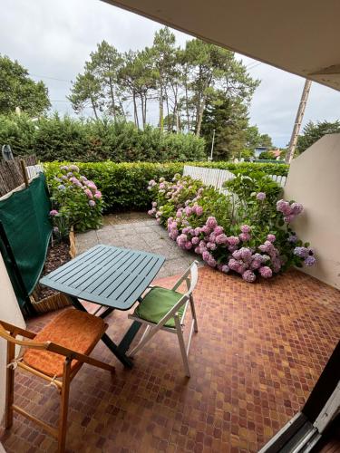 - une terrasse avec une table, des chaises et des fleurs dans l'établissement La belle onde, à Mimizan-Plage