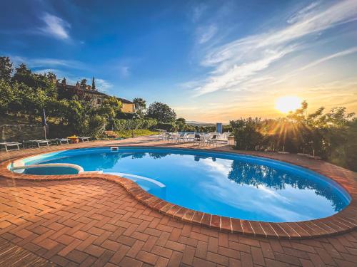 a large swimming pool in a yard with a sunset at Agriturismo Tenuta Badia in Paciano