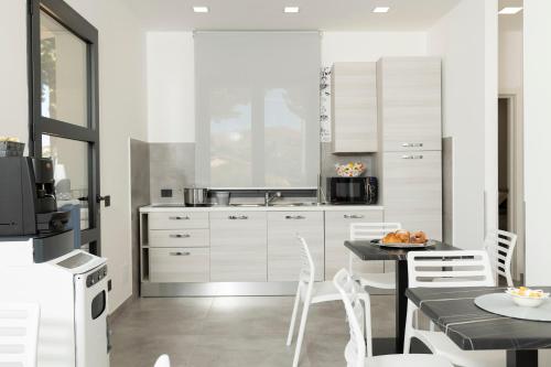 a kitchen with white cabinets and a table and chairs at Dream's Rooms Salemi in Ulmi