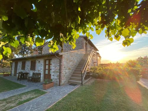 a stone house with a table and chairs in a yard at Agriturismo Tenuta Badia in Paciano