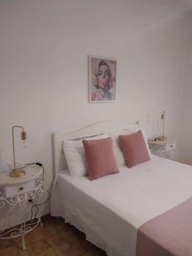 a white bed with two pink pillows in a bedroom at RosaBela in Odiáxere