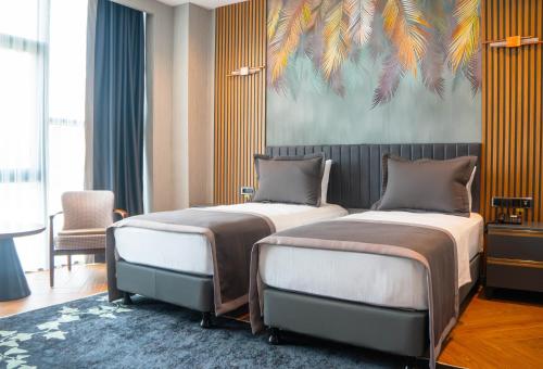 two beds in a room with a painting on the wall at ivy Hotel Spa in Yalova