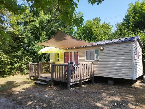 une petite maison avec une véranda et un parasol dans l'établissement Camping Del Padel, à Les Avenières