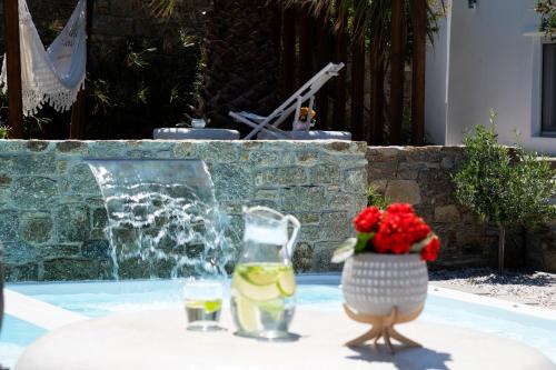 a bird sitting on a table with drinks and a vase of flowers at Myconian Theros Luxury Suites in Ano Mera