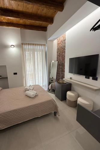 a bedroom with a bed and a flat screen tv at Aria Suites Cefalù in Cefalù