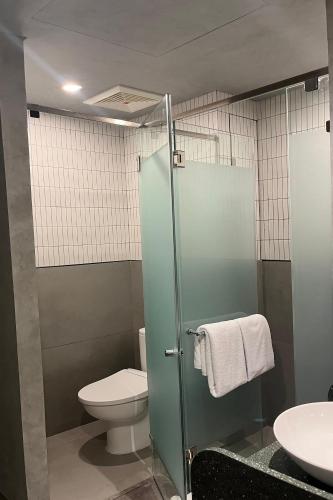 a bathroom with a toilet and a glass shower stall at ATOOI Hotel Alam Sutera in Serpong