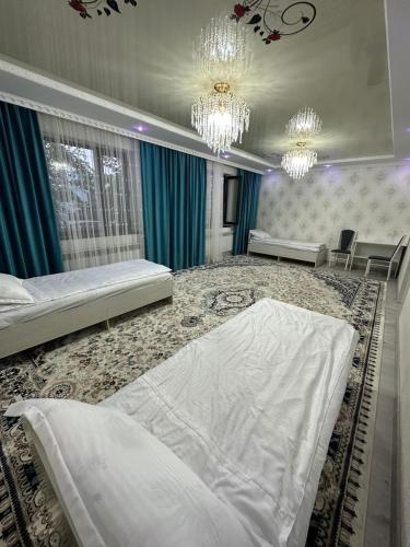 a bedroom with a large white bed and chandeliers at Guest House NAZIRA in Kazarman
