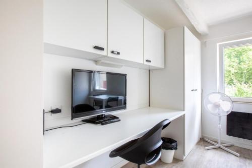 a white room with a desk with a tv and a chair at DeLuxe Studio Lumineux et Rénové, Parking Gratuit, MULHOUSE CENTRE in Mulhouse