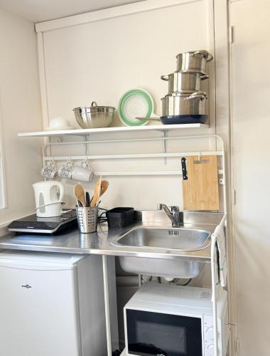 une cuisine avec un évier et un micro-ondes dans l'établissement Studio Platanes 9 - Proche Disneyland - Parking gratuit - Meaux, à Meaux
