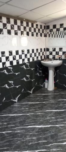 a bathroom with a sink and black and white checkered walls at Holiday Home Rathnaella in Hassalaka