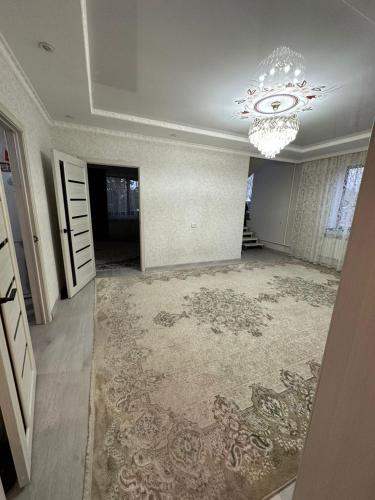 a living room with a chandelier and a large rug at Guest House NAZIRA in Kazarman