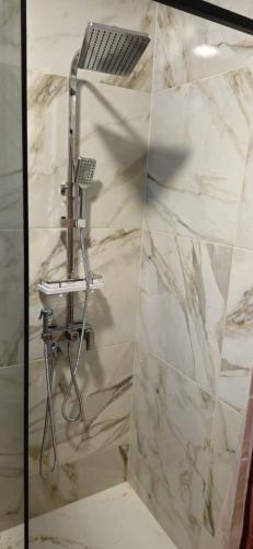 a shower in a bathroom with a white marble wall at Apartments Dubrava 5 in Zagreb
