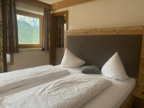 a bedroom with a bed with white sheets and a window at Haus Sonneck in Nauders