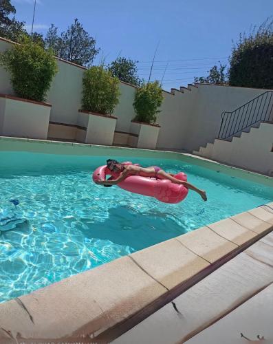 une femme dans un radeau rose dans une piscine dans l'établissement Maison avec piscine VIVES 8 couchages 4 chambres, à Vivès