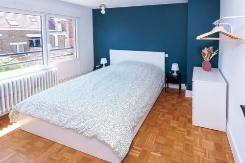 a bedroom with a white bed and a blue wall at Une escale à Malo in Dunkerque