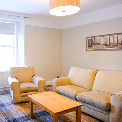 a living room with two couches and a coffee table at Glen Mhor Hotel at Uile-bheist 'Brewstillery' in Inverness