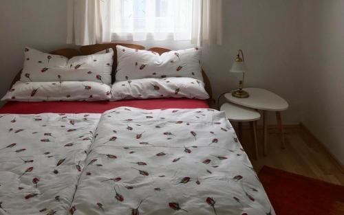 a bed with a white blanket with cherries on it at Haus Schartner Aloisia in Altaussee