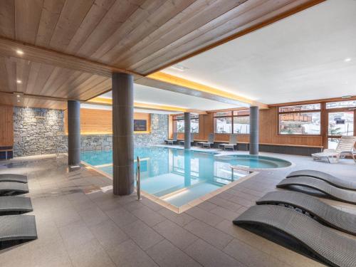une piscine dans un immeuble avec des chaises dans l'établissement Loft spacieux avec spa, piscine, salle de sport et parking - FR-1-809-4, aux Saisies