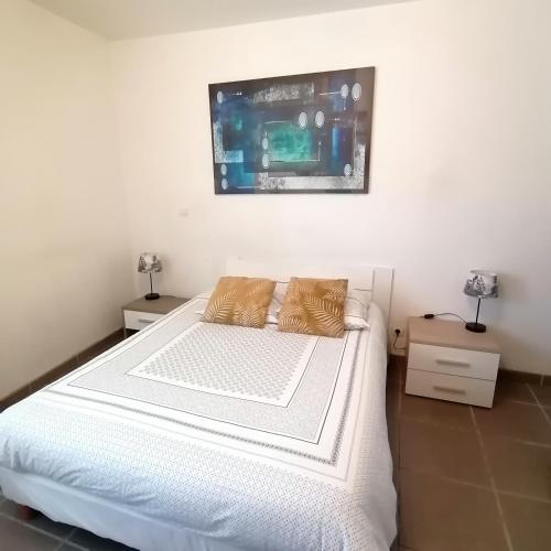 a bedroom with a white bed and two night stands at Appartement 39 m2 Wifi parking gratuit proche Pont du Gard in Remoulins