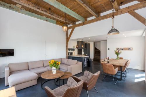 a living room with a couch and a table and chairs at Welcome in - Vakantiehuis 't Zwartje met ruime tuin I Lepelstraat 18B in Vrouwenpolder