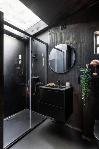a black bathroom with a sink and a mirror at Cabins in the woods with wellness in Brasschaat